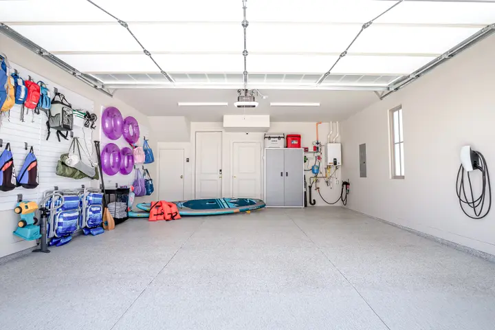 Two-car garage with open parking space, organized vacation gear, and Tesla EV charger