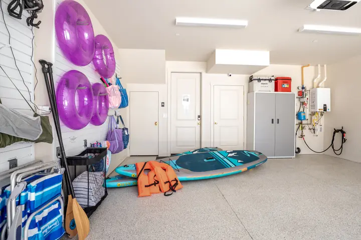 Paddleboards, life jackets, pool floats, and beach gear stored in the garage